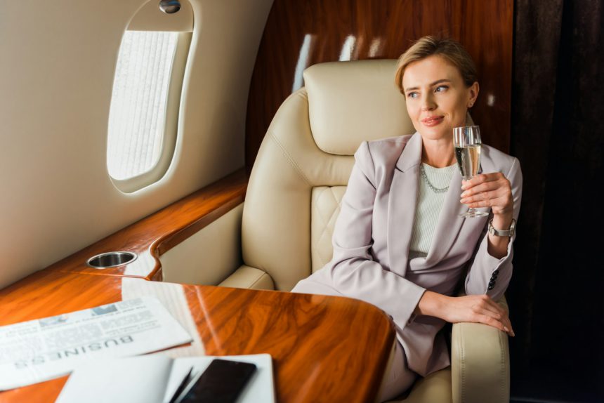 happy businesswoman holding champagne glass in private plane