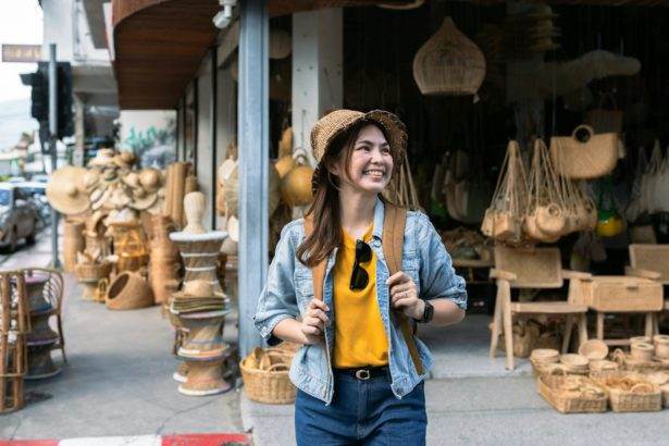 Young female tourist walking across the street and looking at camera while traveling in local market